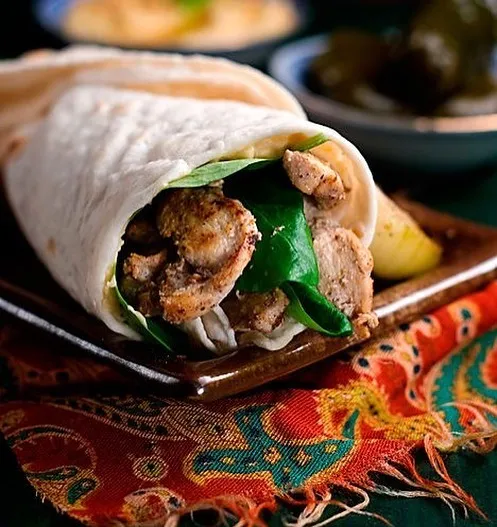 Chicken shawarma wrap, halved, on a patterned cloth