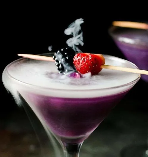 A purple mocktail with smoke rising from the glass