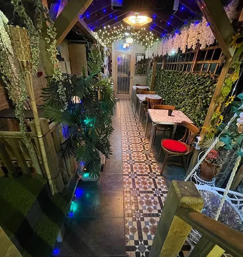 The courtyard: patterned tiled floor, fairy lights overhead, greenery and tables set for the evening
