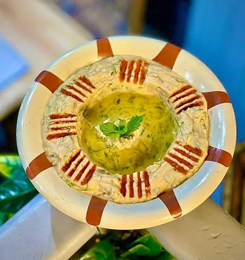 Hommous with olive oil, chilli and fresh mint, on a striped plate