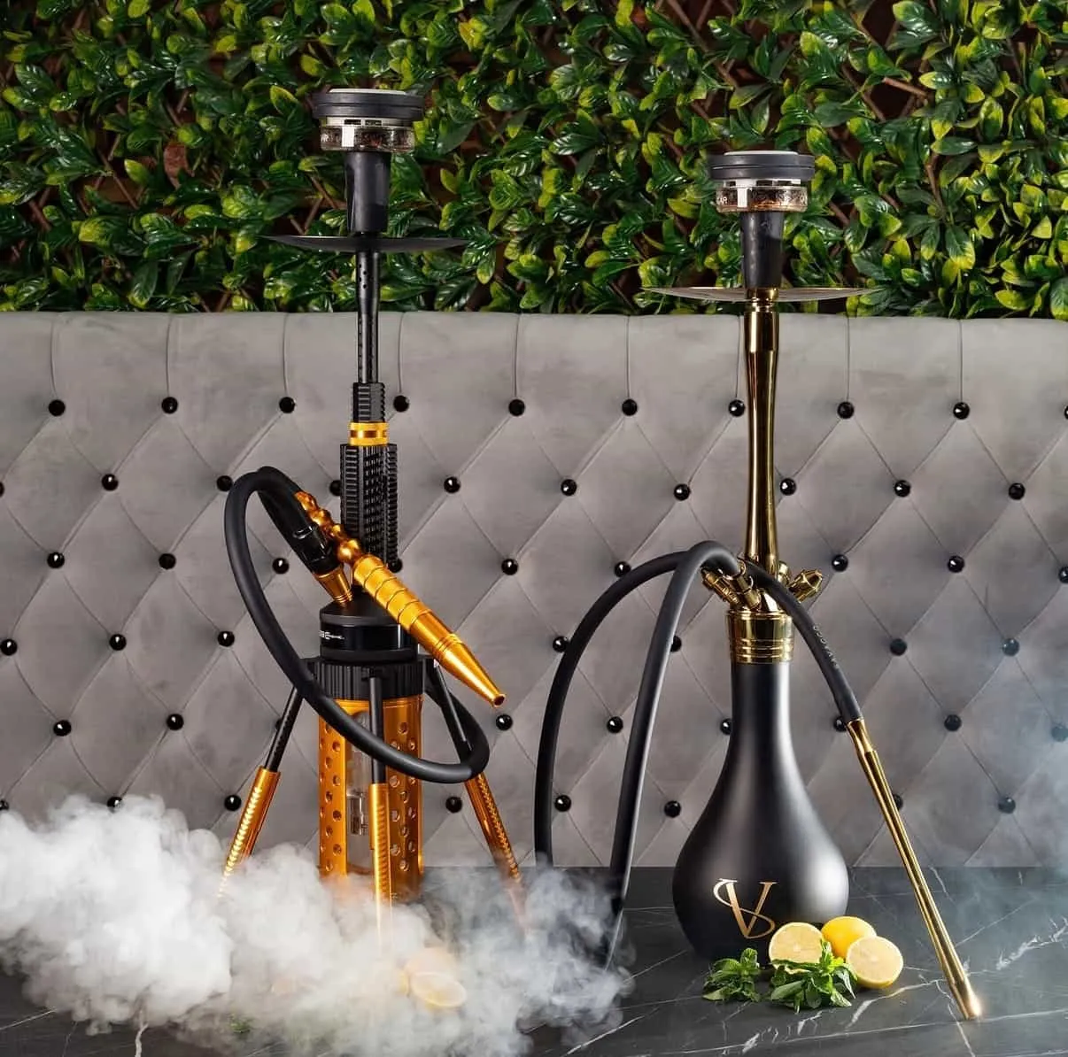 Two shisha pipes on a marble table in the lounge, in front of a tufted grey banquette and a wall of greenery